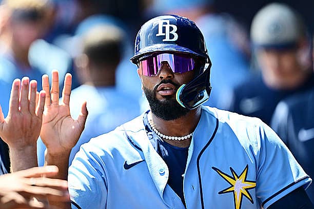 NORTH PORT, FLORIDA – MARCH 24: Junior Caminero #13 of the Tampa Bay Rays celebrates with teammates in the dugout after scor…