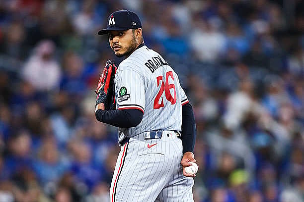 TORONTO, CANADA – APRIL 12: Taj Bradley #26 of the Minnesota Twins looks to first base before delivering a pitch in the four…