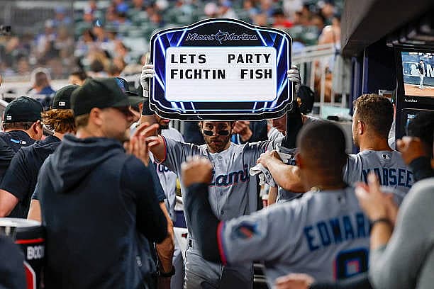 ATLANTA, GEORGIA – APRIL 13: Connor Norby #1 of the Miami Marlins celebrates with teammates in the dugouts after hitting a h…