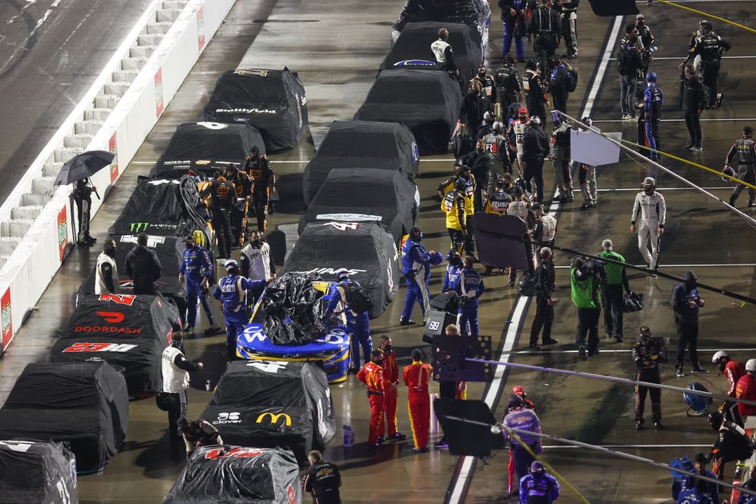 Apr 10, 2021; Martinsville, Virginia, USA; NASCAR Cup Series pit crews cover cars during a rain delay during the Blue-Emu Maximum Pain Relief 500 at Martinsville Speedway. Mandatory Credit: Ryan Hunt-USA TODAY Sports