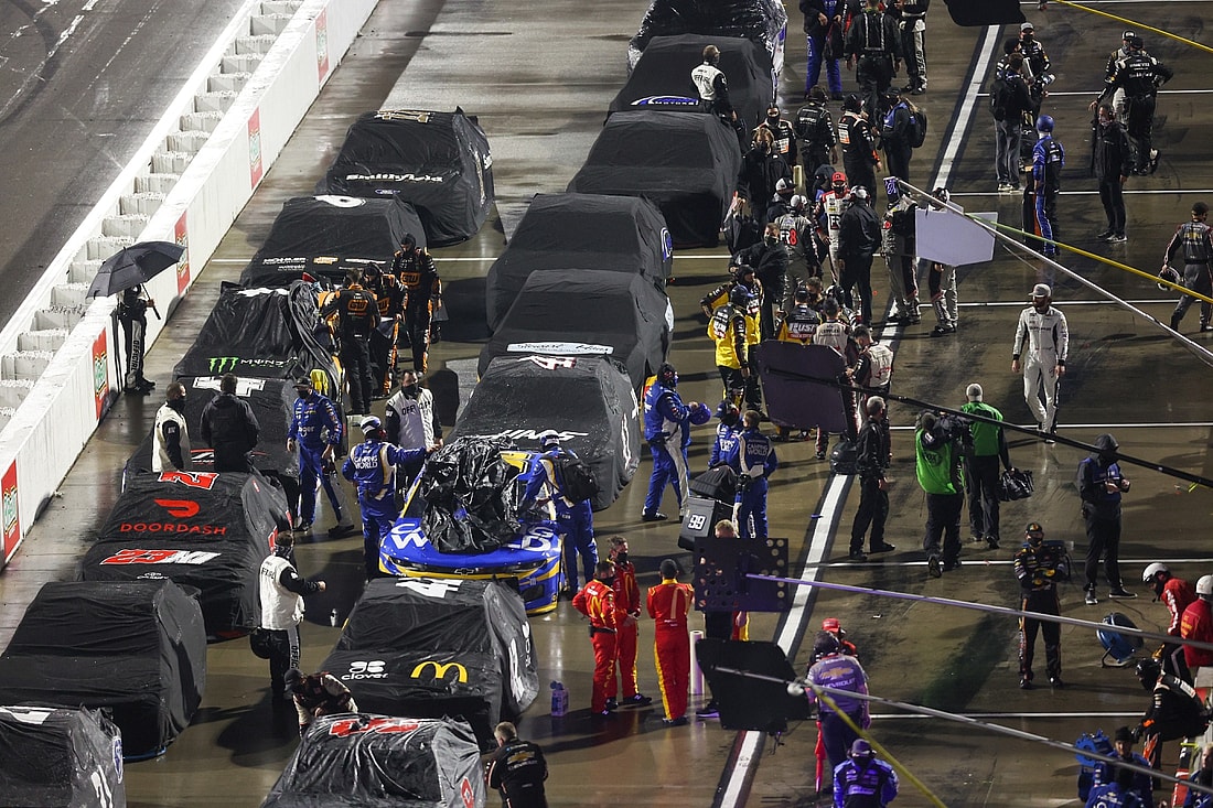Apr 10, 2021; Martinsville, Virginia, USA; NASCAR Cup Series pit crews cover cars during a rain delay during the Blue-Emu Maximum Pain Relief 500 at Martinsville Speedway. Mandatory Credit: Ryan Hunt-USA TODAY Sports