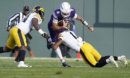 Nov 4, 2023; Chicago, Illinois, USA; Iowa Hawkeyes defensive back Xavier Nwankpa (1) tackles Northwestern Wildcats quarterback Brendan Sullivan (6) during the first half at Wrigley Field. Mandatory Credit: David Banks-USA TODAY Sports