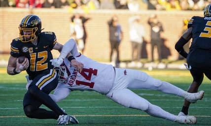 Nov 25, 2022; Columbia, Missouri, USA; Missouri Tigers quarterback Brady Cook (12) is tackled by Arkansas Razorbacks defensive lineman Jordan Domineck (14) during the first half at Faurot Field at Memorial Stadium. Mandatory Credit: Denny Medley-USA TODAY Sports