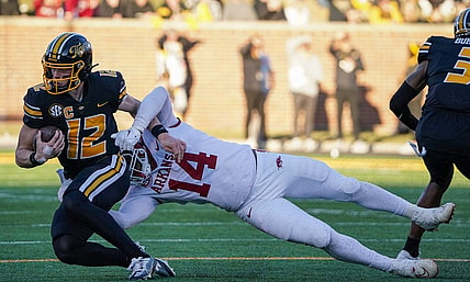 Nov 25, 2022; Columbia, Missouri, USA; Missouri Tigers quarterback Brady Cook (12) is tackled by Arkansas Razorbacks defensive lineman Jordan Domineck (14) during the first half at Faurot Field at Memorial Stadium. Mandatory Credit: Denny Medley-USA TODAY Sports