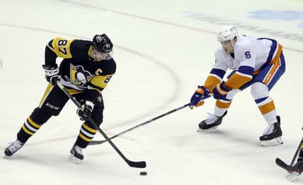 Feb 20, 2021; Pittsburgh, Pennsylvania, USA;  Pittsburgh Penguins center Sidney Crosby (87) handles the puck as New York Islanders defenseman Ryan Pulock (6) defends during the first period at PPG Paints Arena. Mandatory Credit: Charles LeClaire-USA TODAY Sports
