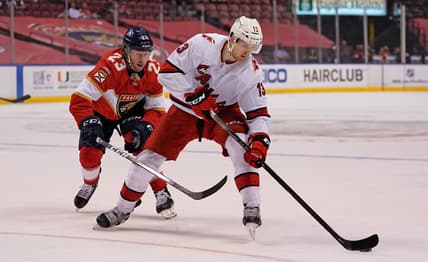 Mar 1, 2021; Sunrise, Florida, USA; Florida Panthers center Carter Verhaeghe (23) reaches for the puck on Carolina Hurricanes left wing Warren Foegele (13) during the first period at BB&T Center. Mandatory Credit: Jasen Vinlove-USA TODAY Sports