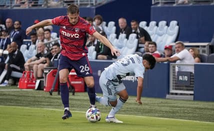 May 10, 2022; Kansas City, Kansas, USA; FC Dallas defender Lucas Bartlett (26) and Sporting Kansas City midfielder Ozzie Cisneros (25) fight for the ball during the first half at Children's Mercy Park. Mandatory Credit: Denny Medley-USA TODAY Sports