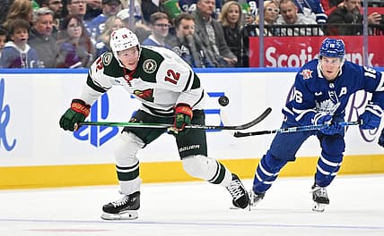 Oct 14, 2023; Toronto, Ontario, CAN;  Minnesota Wild forward Matt Boldy (12) pursues the puck ahead of Toronto Maple Leafs forward Mitchell Marner (16) in the second  period at Scotiabank Arena. Mandatory Credit: Dan Hamilton-USA TODAY Sports