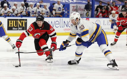 Feb 25, 2021; Buffalo, New York, USA;  New Jersey Devils left wing Jesper Bratt (63) and Buffalo Sabres defenseman Colin Miller (33) reach for a loose puck during the first period at KeyBank Center. Mandatory Credit: Timothy T. Ludwig-USA TODAY Sports
