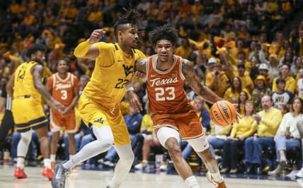 Jan 13, 2024; Morgantown, West Virginia, USA; Texas Longhorns forward Dillon Mitchell (23) drives baseline against West Virginia Mountaineers forward Josiah Harris (22) during the first half at WVU Coliseum. Mandatory Credit: Ben Queen-USA TODAY Sports