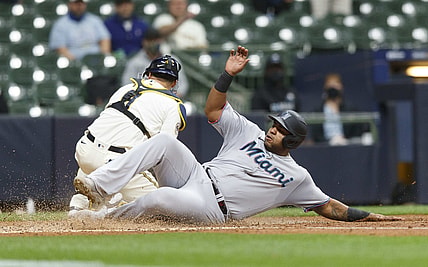 Apr 26, 2021; Milwaukee, Wisconsin, USA; Miami Marlins first baseman Jes s Aguilar (24) slides into home to score a run in front of Milwaukee Brewers catcher Manny Pi a (9) during the fourth inning at American Family Field. Mandatory Credit: Jeff Hanisch-USA TODAY Sports