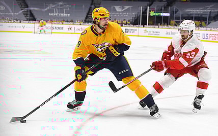 Feb 11, 2021; Nashville, Tennessee, USA; Nashville Predators left wing Filip Forsberg (9) looks to pass the puck as he is defended by Detroit Red Wings left wing Darren Helm (43) during the first period at Bridgestone Arena. Mandatory Credit: Christopher Hanewinckel-USA TODAY Sports