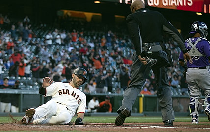 Apr 28, 2021; San Francisco, California, USA; San Francisco Giants catcher Curt Casali (left) slides safely home as he scores on a two-run RBI single hit by first baseman Brandon Belt (9) against the Colorado Rockies during the second inning as home plate umpire CB Bucknor watches at Oracle Park. Mandatory Credit: D. Ross Cameron-USA TODAY Sports