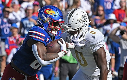 Oct 7, 2023; Lawrence, Kansas, USA;  Kansas Jayhawks running back Daniel Hishaw Jr. (20) runs up field against UCF Knights linebacker Jason Johnson (0) during the first half at David Booth Kansas Memorial Stadium. Mandatory Credit: Peter Aiken-USA TODAY Sports