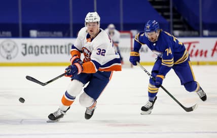 May 4, 2021; Buffalo, New York, USA;  New York Islanders left wing Ross Johnston (32) shoots the puck up ice as Buffalo Sabres center Rasmus Asplund (74) tries to defend during the first period at KeyBank Center. Mandatory Credit: Timothy T. Ludwig-USA TODAY Sports