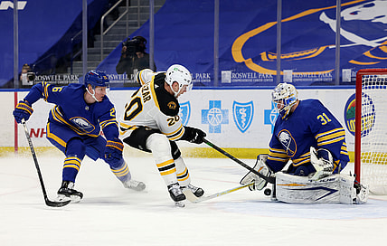 Apr 22, 2021; Buffalo, New York, USA; Buffalo Sabres defenseman Rasmus Dahlin (26) tries to defend as Boston Bruins center Curtis Lazar (20) takes a shot on Buffalo Sabres goaltender Dustin Tokarski (31) during the first period at KeyBank Center. Mandatory Credit: Timothy T. Ludwig-USA TODAY Sports