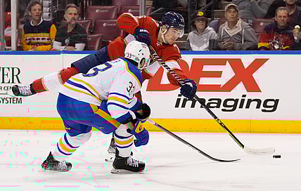 Dec 2, 2021; Sunrise, Florida, USA; Florida Panthers left wing Frank Vatrano (77) shoots the puck in front of Buffalo Sabres defenseman Colin Miller (33) during the second period at FLA Live Arena. Mandatory Credit: Jasen Vinlove-USA TODAY Sports