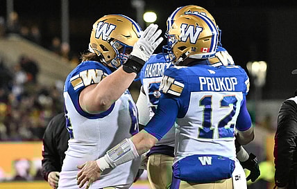 Nov 19, 2023; Hamilton, Ontario, CAN;  Winnipeg Blue Bombers quarterback Dakota Prukop (12) celebrates with offensive lineman Liam Dobson (64) after scoring a touchdown against the Montreal Alouettes in the first half at Tim Hortons Field. Mandatory Credit: Dan Hamilton-USA TODAY Sports