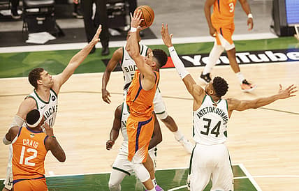 Jul 14, 2021; Milwaukee, Wisconsin, USA; Phoenix Suns guard Devin Booker (1) shoots between Milwaukee Bucks center Brook Lopez (11) and forward Giannis Antetokounmpo (34) during the third quarter during game four of the 2021 NBA Finals at Fiserv Forum. Mandatory Credit: Jeff Hanisch-USA TODAY Sports