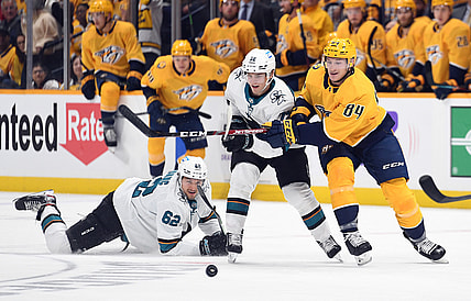 Oct 26, 2021; Nashville, Tennessee, USA; Nashville Predators left wing Tanner Jeannot (84) battles for a loose puck with San Jose Sharks right wing Kevin Labanc (62) and San Jose Sharks left wing William Eklund (72) during the first period at Bridgestone Arena. Mandatory Credit: Christopher Hanewinckel-USA TODAY Sports