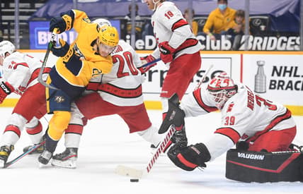 May 8, 2021; Nashville, Tennessee, USA; Nashville Predators right wing Eeli Tolvanen (28) tries to get around Carolina Hurricanes right wing Sebastian Aho (20) before the puck is covered by Carolina Hurricanes goaltender Alex Nedeljkovic (39) during the first period at Bridgestone Arena. Mandatory Credit: Christopher Hanewinckel-USA TODAY Sports