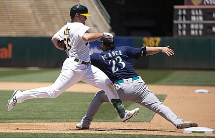 Jun 23, 2022; Oakland, California, USA; Seattle Mariners first baseman Ty France (23) gets his glove caught under the arm of Oakland Athletics third baseman Sheldon Neuse (26) as he reaches for the throw during the fifth inning at RingCentral Coliseum. France was injured on the play, and left the game. Neuse was safe at first. Mandatory Credit: D. Ross Cameron-USA TODAY Sports