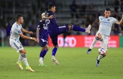 Aug 21, 2021; Orlando, Florida, USA; Orlando City defender Antonio Carlos (25) controls the ball between Chicago Fire midfielder Stanislav Ivanov (99) and midfielder Luka Stojanovic (8) at Orlando City Stadium. Mandatory Credit: Matt Stamey-USA TODAY Sports
