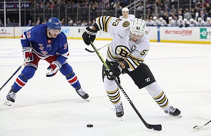 Nov 25, 2023; New York, New York, USA; Boston Bruins left wing Brad Marchand (63) plays the puck in front of New York Rangers left wing Jimmy Vesey (26) during the third period at Madison Square Garden. Mandatory Credit: Danny Wild-USA TODAY Sports
