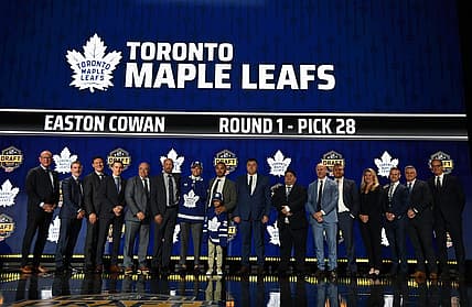Jun 28, 2023; Nashville, Tennessee, USA; Toronto Maple Leafs draft pick Easton Cowan stands with Leafs staff after being selected with the twenty eighth pick in round one of the 2023 NHL Draft at Bridgestone Arena. Mandatory Credit: Christopher Hanewinckel-USA TODAY Sports