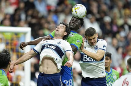Sep 17, 2022; Vancouver, British Columbia, CAN; Seattle Sounders defender Yeimar Gomez Andrade (28) gets his head on the ball while battling with Vancouver Whitecaps forward Brian White (24) and defender Ranko Veselinovic (4) in the first half at BC Place. Mandatory Credit: Bob Frid-USA TODAY Sports