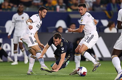Jul 8, 2023; Carson, California, USA; Philadelphia Union midfielder Deniel Gazdag (10) dribbles against Los Angeles Galaxy midfielder Gaston Brugman (5) and midfielder Marco Delgado (8) during the first half at Dignity Health Sports Park. Mandatory Credit: Jason Parkhurst-USA TODAY Sports