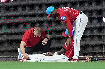 May 13, 2023; Miami, Florida, USA;  Miami Marlins left fielder Bryan De La Cruz (14) holds up center fielder Jazz Chisholm Jr. (2) as he has his leg examined after colliding with the centerfield wall in the eighth inning against the Cincinnati Reds at loanDepot Park. Mandatory Credit: Jim Rassol-USA TODAY Sports