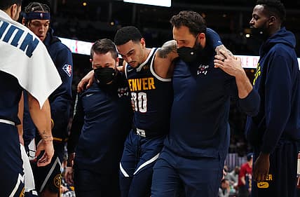 Dec 15, 2021; Denver, Colorado, USA; Denver Nuggets guard Markus Howard (00) is helped off the court following an injury in the fourth quarter against the Minnesota Timberwolves at Ball Arena. Mandatory Credit: Ron Chenoy-USA TODAY Sports