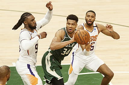 Jul 11, 2021; Milwaukee, Wisconsin, USA; Milwaukee Bucks forward Giannis Antetokounmpo (34) passes the ball under pressure from Phoenix Suns forward Jae Crowder (99) and forward Mikal Bridges (25) during the second quarter during game three of the 2021 NBA Finals at Fiserv Forum. Mandatory Credit: Jeff Hanisch-USA TODAY Sports