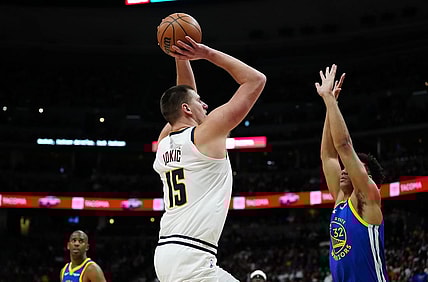 Dec 25, 2023; Denver, Colorado, USA; Denver Nuggets center Nikola Jokic (15) prepares to shoot over Golden State Warriors forward Trayce Jackson-Davis (32) in the second half at Ball Arena. Mandatory Credit: Ron Chenoy-USA TODAY Sports
