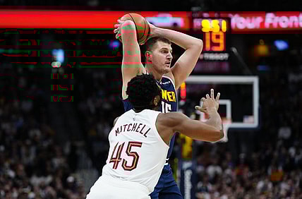 Mar 31, 2024; Denver, Colorado, USA; Denver Nuggets center Nikola Jokic (15) prepares to pass the ball over Cleveland Cavaliers guard Donovan Mitchell (45) in the first quarter at Ball Arena. Mandatory Credit: Ron Chenoy-USA TODAY Sports