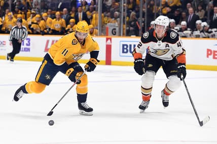 Nov 22, 2021; Nashville, Tennessee, USA; Nashville Predators center Luke Kunin (11) skates with the puck before pressure from Anaheim Ducks defenseman Josh Manson (42) during the first period at Bridgestone Arena. Mandatory Credit: Christopher Hanewinckel-USA TODAY Sports