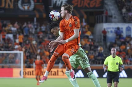 May 27, 2023; Houston, Texas, USA; Houston Dynamo FC forward Thor Ulfarsson (34) attempts to head the ball away from Austin FC defender Julio Cascante (18) during the match at Shell Energy Stadium. Mandatory Credit: Troy Taormina-USA TODAY Sports