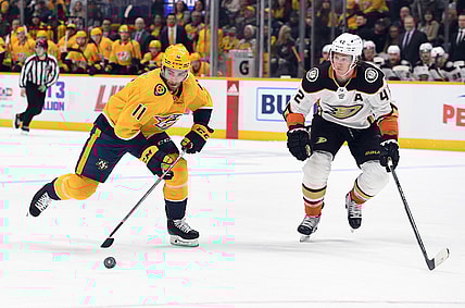 Nov 22, 2021; Nashville, Tennessee, USA; Nashville Predators center Luke Kunin (11) skates with the puck before pressure from Anaheim Ducks defenseman Josh Manson (42) during the first period at Bridgestone Arena. Mandatory Credit: Christopher Hanewinckel-USA TODAY Sports