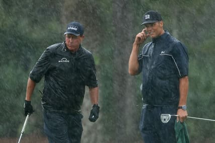 May 24, 2020; Hobe Sound, FL, USA; Phil Mickelson and NFL player Tom Brady of the Tampa Bay Buccaneers react on the 13th green in the rain during The Match: Champions for Charity golf round at the Medalist Golf Club.  Mandatory Credit: Handout Photo by Getty Images for The Match via USA TODAY Sports