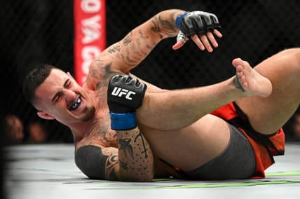 Jul 23, 2022; London, United Kingdom;  Tom Aspinall (blue gloves) falls to the ground while fighting Curtis Blaydes during UFC Fight Night at O2 Arena. Mandatory Credit: Per Haljestam-USA TODAY Sports