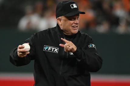 Apr 12, 2022; Baltimore, Maryland, USA;  Umpire Brian O'Nora (7) signals while holding a baseball during the game between the Baltimore Orioles and the Milwaukee Brewers at Oriole Park at Camden Yards. Mandatory Credit: Tommy Gilligan-USA TODAY Sports