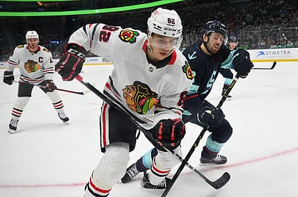 Apr 8, 2023; Seattle, Washington, USA; Chicago Blackhawks defenseman Caleb Jones (82) and Seattle Kraken right wing Oliver Bjorkstrand (22) fight for the puck during the second period at Climate Pledge Arena. Mandatory Credit: Steven Bisig-USA TODAY Sports