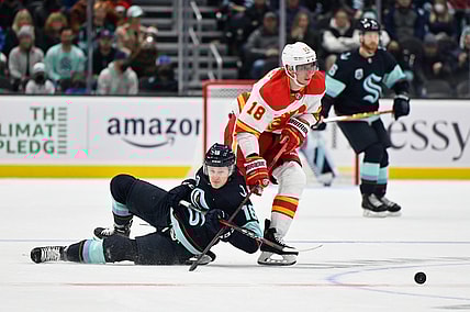 Dec 30, 2021; Seattle, Washington, USA; Seattle Kraken left wing Jared McCann (16) and Calgary Flames center Tyler Pitlick (18) fight for the puck during the first period at Climate Pledge Arena. Mandatory Credit: Steven Bisig-USA TODAY Sports
