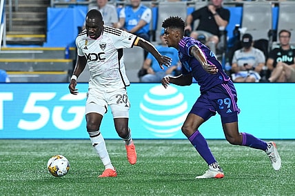 Sep 16, 2023; Charlotte, North Carolina, USA; D.C. United attacker Christian Benteke (20) dribbles the ball past Charlotte FC defender Adilson Malanda (29) in the first half at Bank of America Stadium. Mandatory Credit: Griffin Zetterberg-USA TODAY Sports