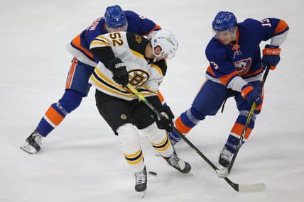 Feb 25, 2021; Uniondale, New York, USA; Boston Bruins center Sean Kuraly (52) plays the puck against New York Islanders defenseman Noah Dobson (8) and center Mathew Barzal (13) during the second period at Nassau Veterans Memorial Coliseum. Mandatory Credit: Brad Penner-USA TODAY Sports