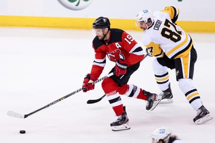 Mar 18, 2021; Newark, New Jersey, USA; New Jersey Devils center Travis Zajac (19) skates with the puck as Pittsburgh Penguins center Sidney Crosby (87) chases during the first period at Prudential Center. Mandatory Credit: Vincent Carchietta-USA TODAY Sports