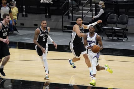 Mar 31, 2021; San Antonio, Texas, USA; Sacramento Kings guard De'Aaron Fox (5) drives to the basket past San Antonio Spurs forward Keldon Johnson (3) and guard Dejounte Murray (5) and center Jakob Poeltl (25) look on in the third quarter at AT&T Center. Mandatory Credit: Scott Wachter-USA TODAY Sports