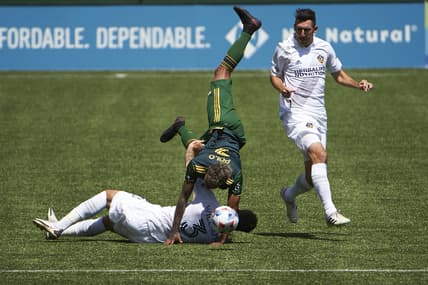 May 22, 2021; Portland, Oregon, USA; Los Angeles Galaxy defender Derrick Williams (3) slides into Portland Timbers forward Andy Polo (7) during the first half at Providence Park. Williams was issued a red card on the play. Mandatory Credit: Troy Wayrynen-USA TODAY Sports