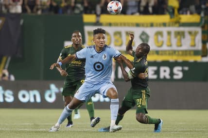 Jun 26, 2021; Portland, Oregon, USA; Minnesota United forward Juan Agudelo (21) and Portland Timbers midfielder Diego Chara (21) battle for the ball during the second half at Providence Park. Mandatory Credit: Soobum Im-USA TODAY Sports